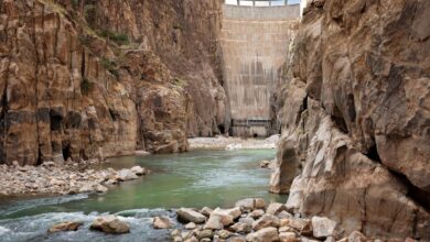 Large hydropower dam with water flowing through spillways in a mountain river valley