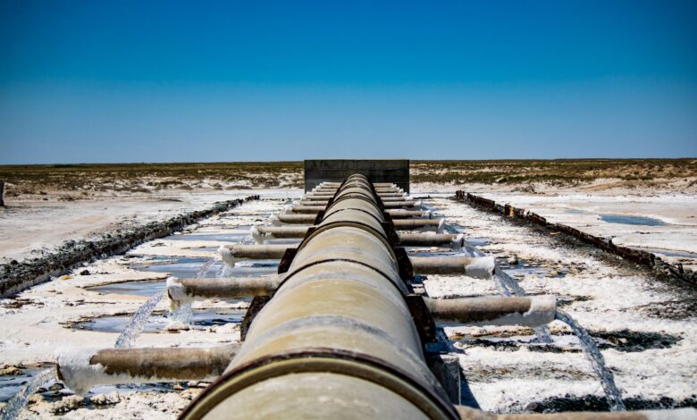 Large coastal desalination facility with pipes and processing equipment near the ocean