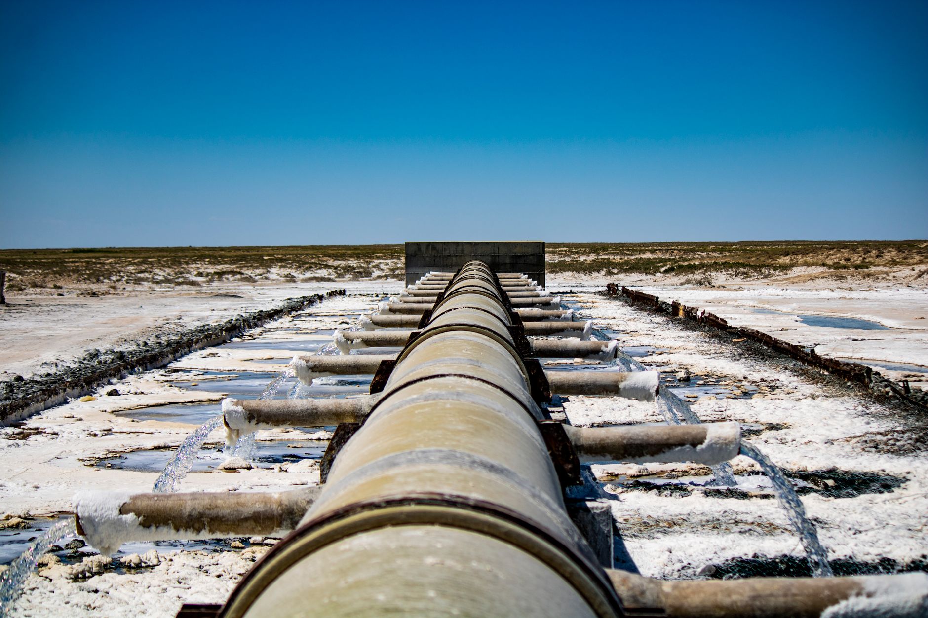 Large coastal desalination facility with pipes and processing equipment near the ocean
