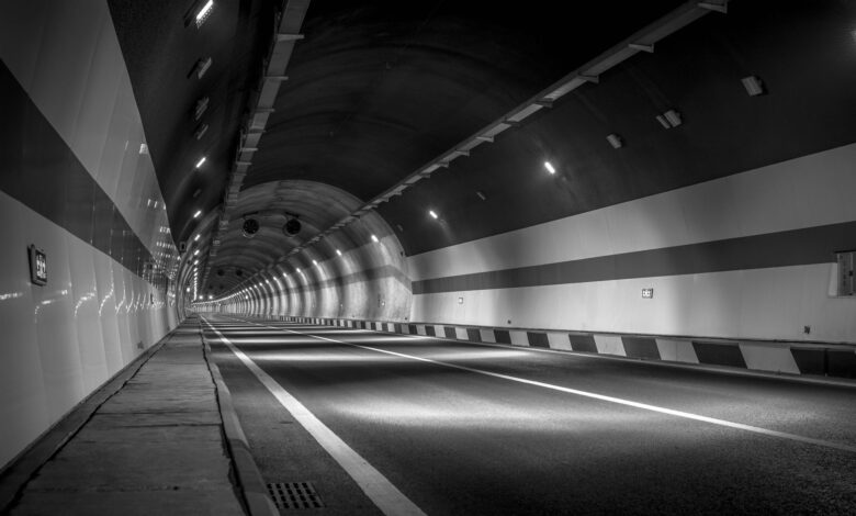 A long illuminated road tunnel with traffic flowing through it