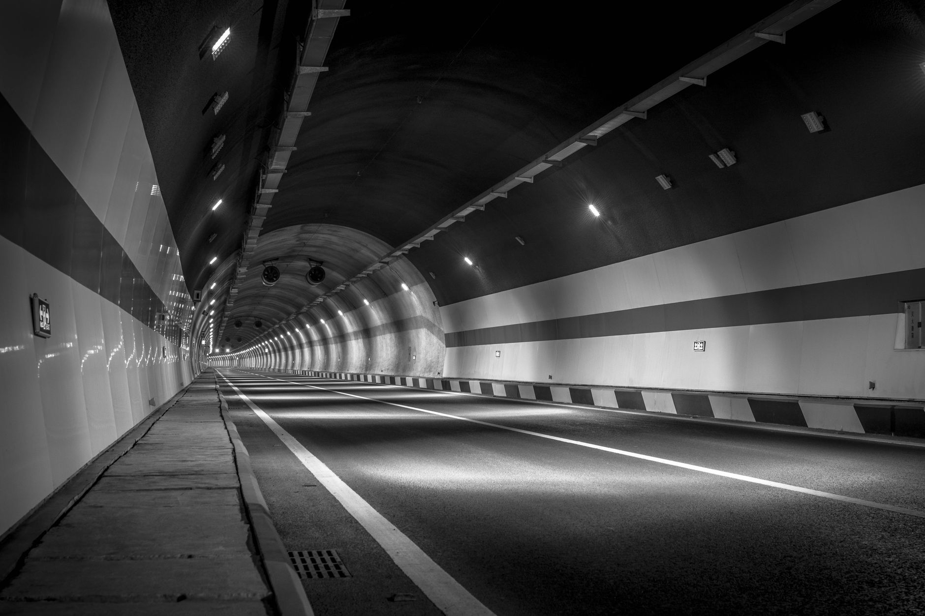 A long illuminated road tunnel with traffic flowing through it