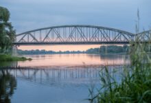 Historic railroad bridge spanning a wide river, viewed from below