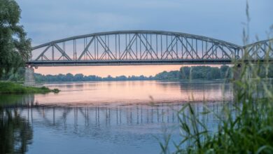 Historic railroad bridge spanning a wide river, viewed from below