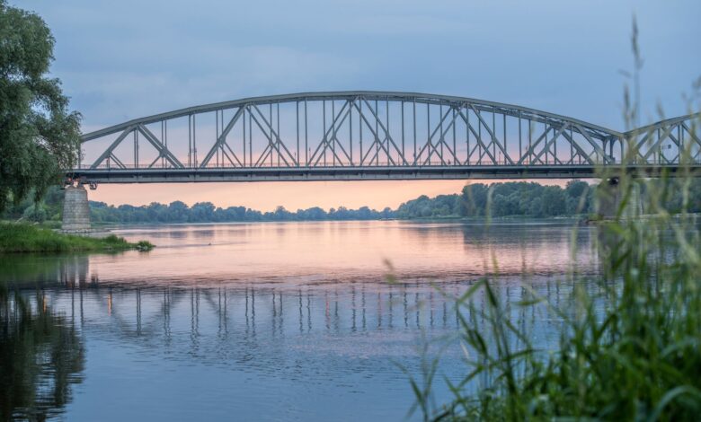 Historic railroad bridge spanning a wide river, viewed from below
