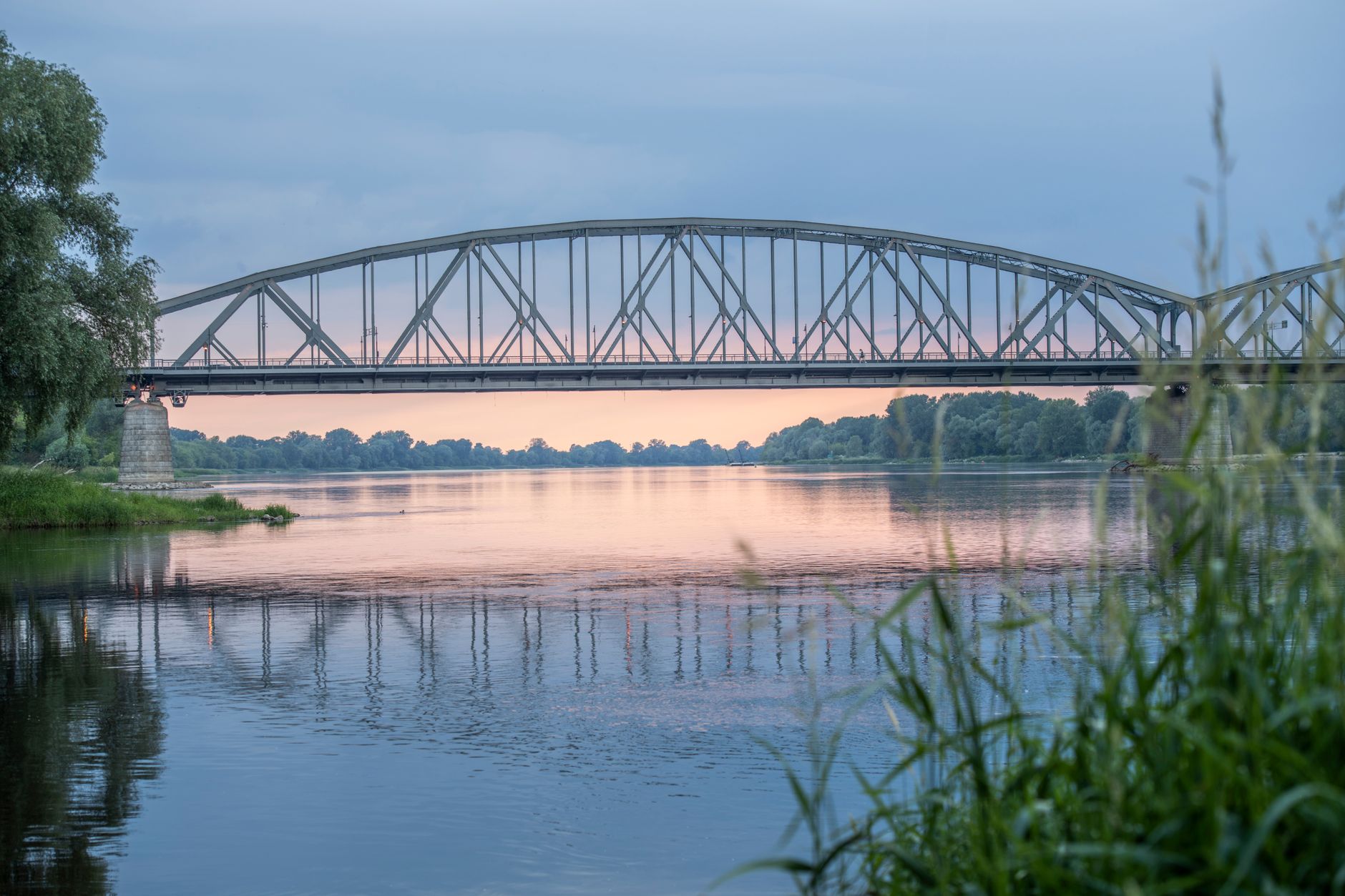 Historic railroad bridge spanning a wide river, viewed from below