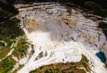 Aerial view of an active stone quarry with extraction equipment and terraced rock face