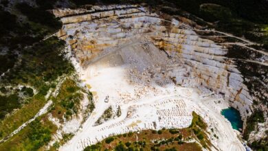Aerial view of an active stone quarry with extraction equipment and terraced rock face