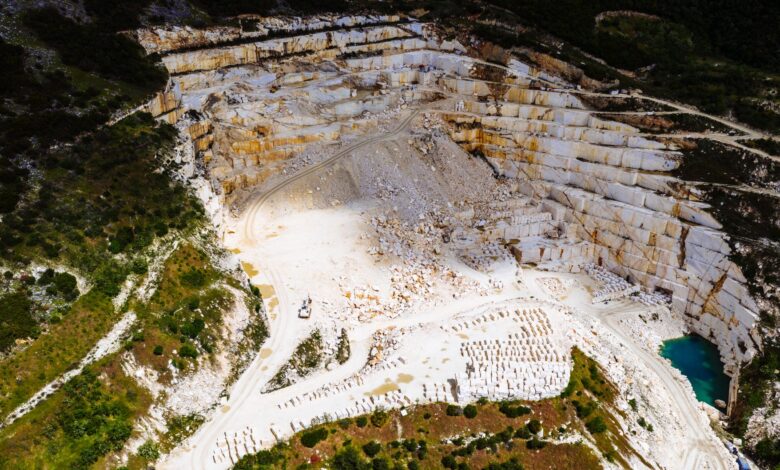 Aerial view of an active stone quarry with extraction equipment and terraced rock face