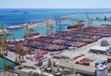 Large industrial export terminal with storage tanks and shipping berths along a coastal port