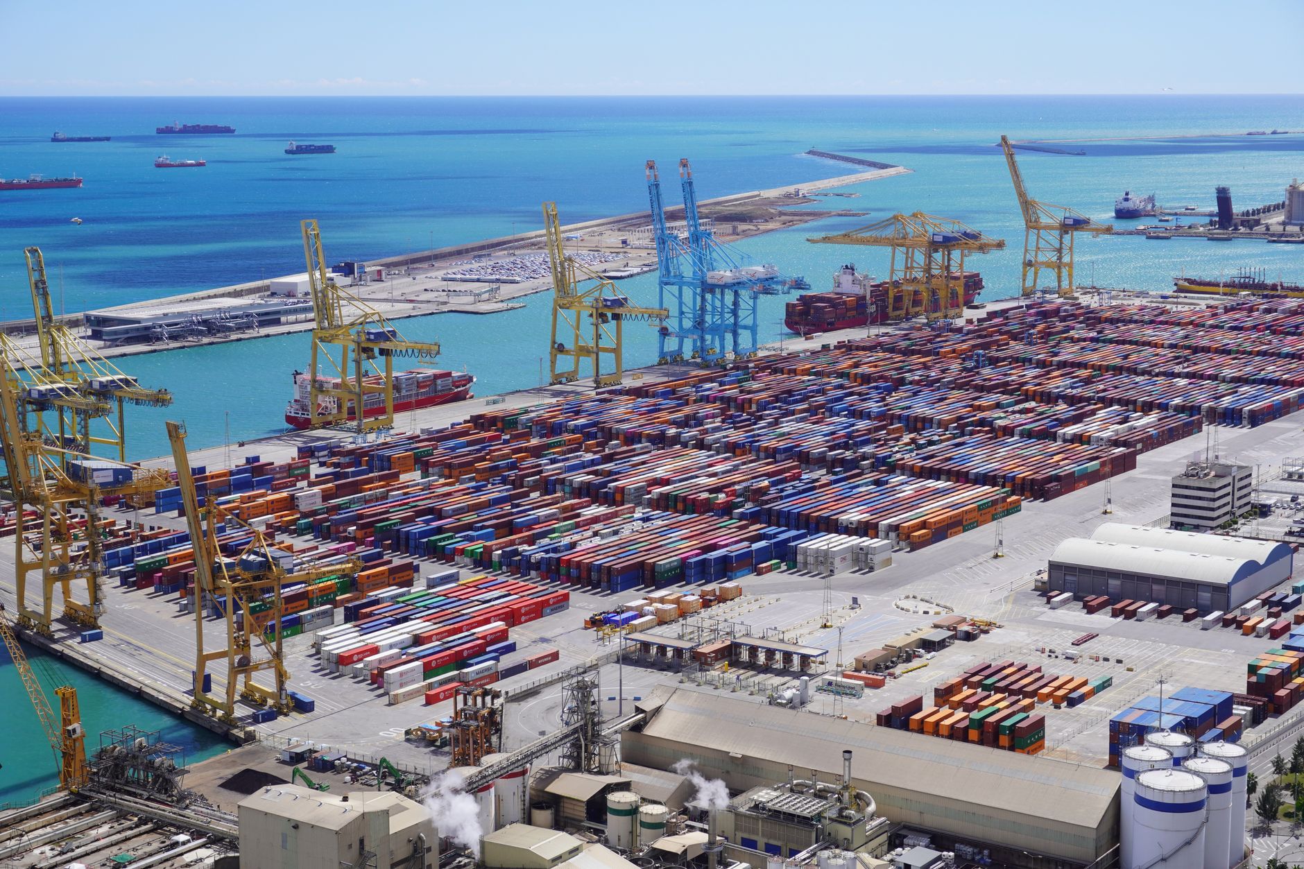 Large industrial export terminal with storage tanks and shipping berths along a coastal port