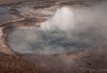 Steam rising from a geothermal energy plant in an open landscape