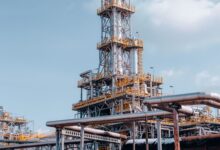Industrial oil field infrastructure in a remote landscape, showing pipes and wellhead equipment