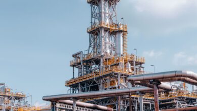 Industrial oil field infrastructure in a remote landscape, showing pipes and wellhead equipment