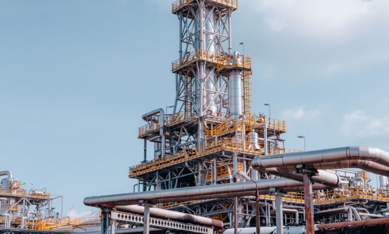Industrial oil field infrastructure in a remote landscape, showing pipes and wellhead equipment