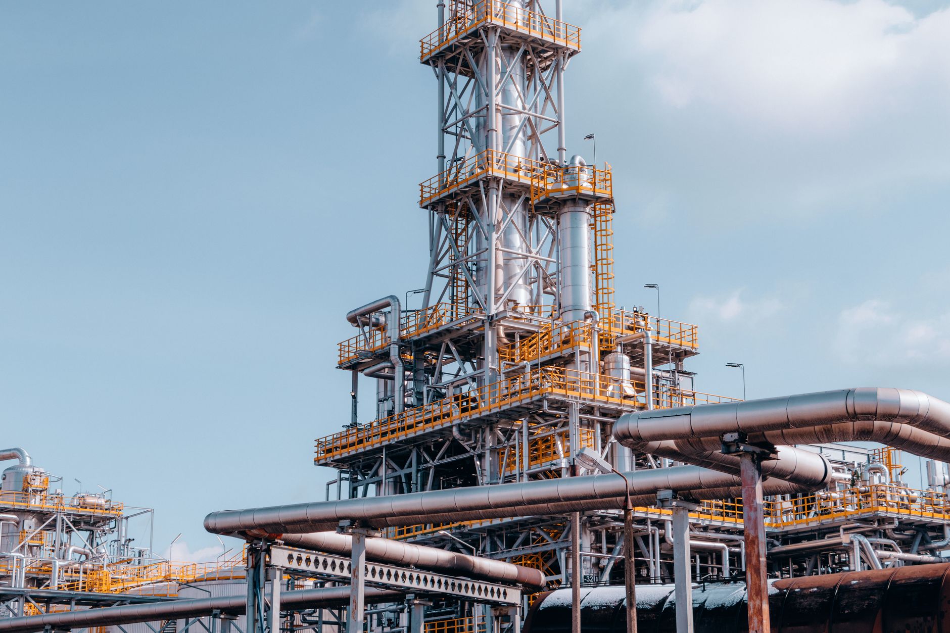 Industrial oil field infrastructure in a remote landscape, showing pipes and wellhead equipment