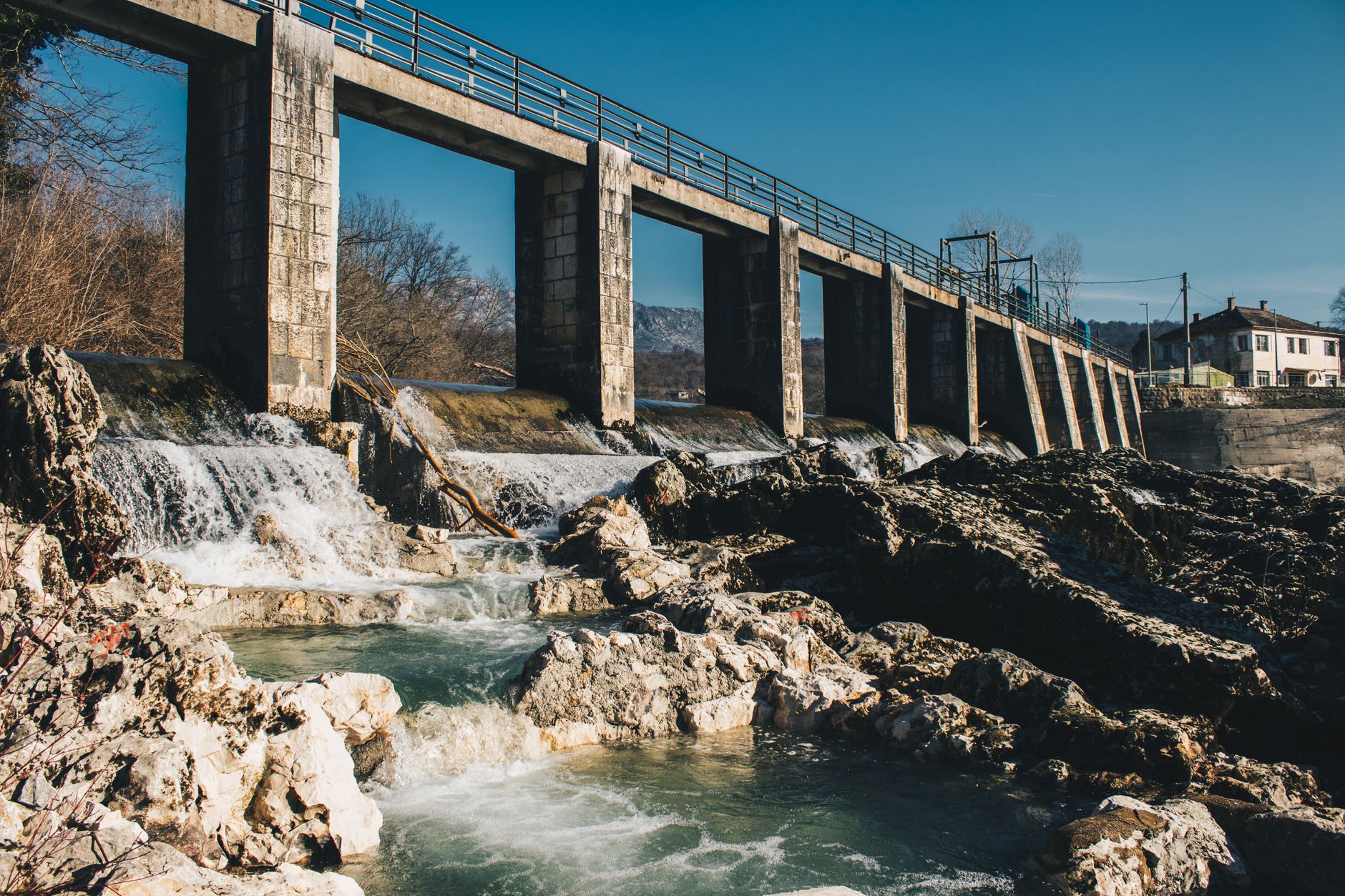A large hydroelectric dam releasing water through spillways in a mountainous river valley