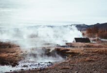 Steam rising from geothermal vents across open land in a volcanic region