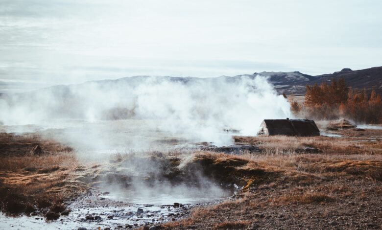 Steam rising from geothermal vents across open land in a volcanic region