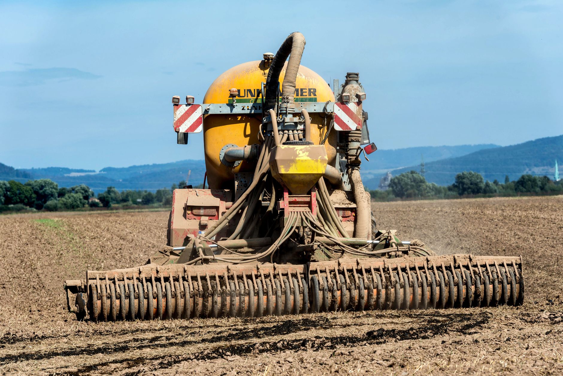 Agricultural fields with fertilizer application equipment working across rows of crops