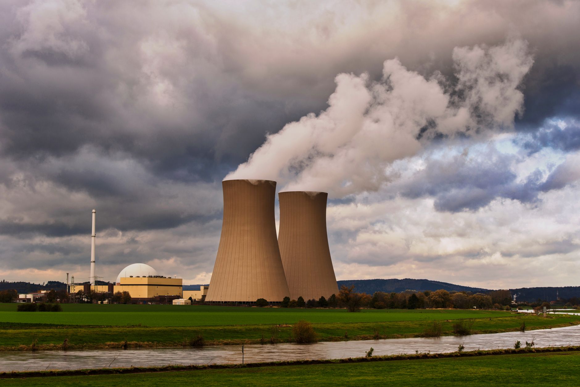 Nuclear power plant cooling towers reflecting in a still water body at dusk
