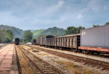 Industrial freight railroad tracks stretching through a rural landscape