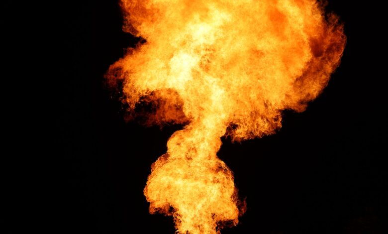 Gas flare burning at an oil production site at dusk