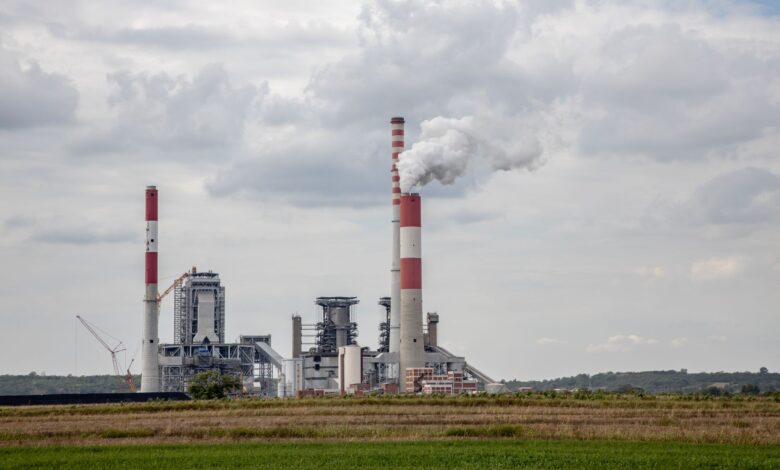 Industrial smokestack emitting gases against a cloudy sky, representing sulfur dioxide emissions from power plants