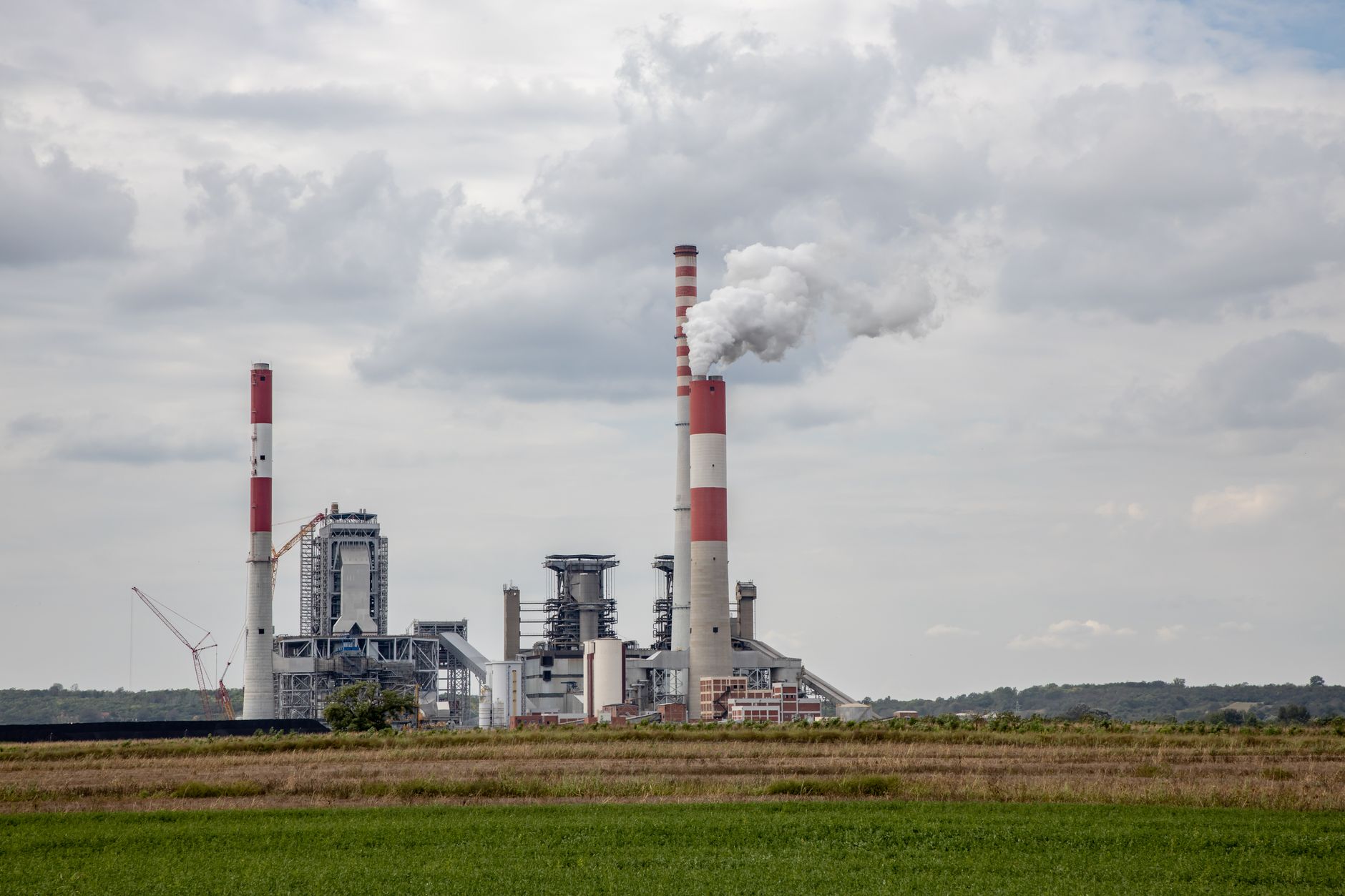 Industrial smokestack emitting gases against a cloudy sky, representing sulfur dioxide emissions from power plants