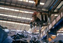 Workers inside a titanium metal processing facility with industrial equipment