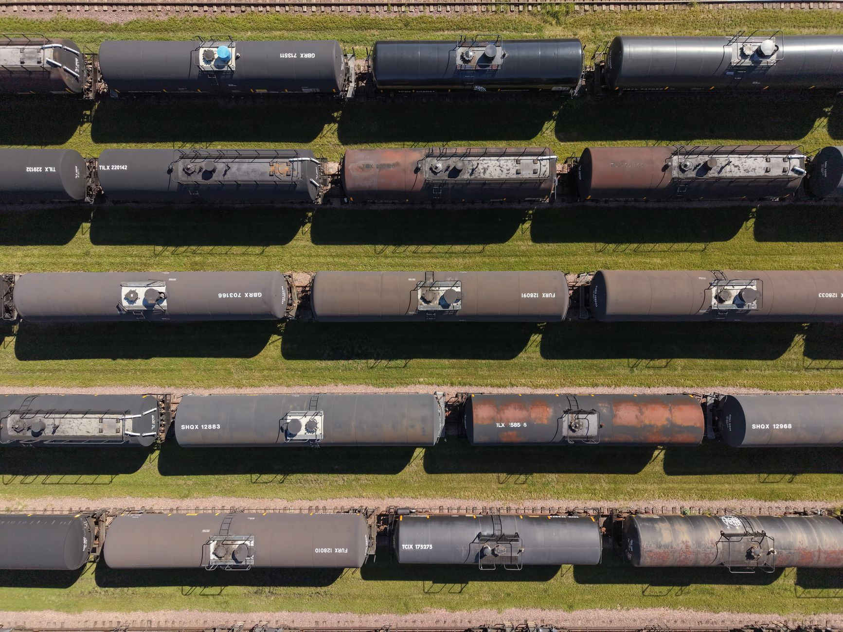 Industrial tank rail cars lined up on freight tracks at a rail yard