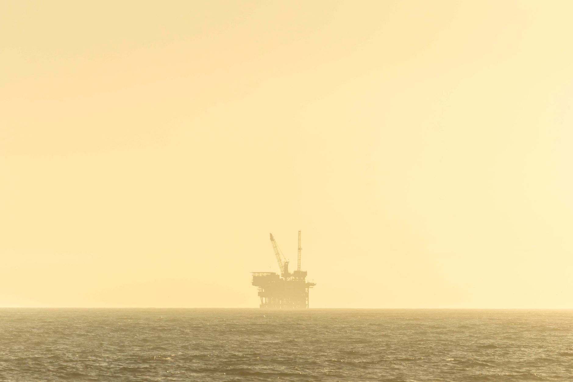 Aerial view of oil drilling operations across a wide basin with multiple active well sites